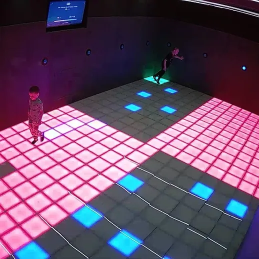 Дети играют в интерактивной комнате с цветными световыми плитками в развлекательном центре