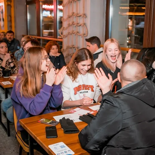 Вечер викторин в уютном кафе с друзьями за столом, радостные лица и атмосфера веселья