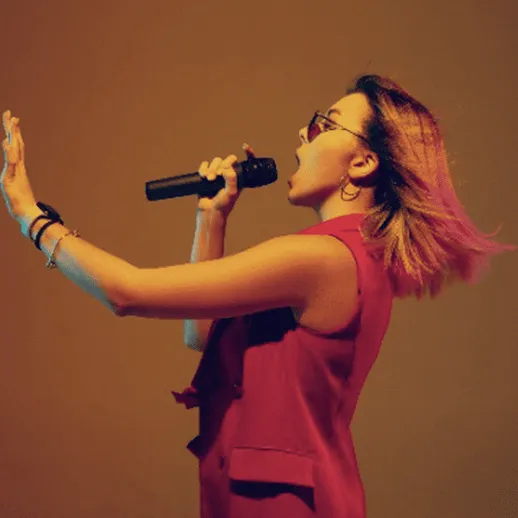 Выступление певицы на сцене с микрофоном в ярком освещении и энергичными движениями