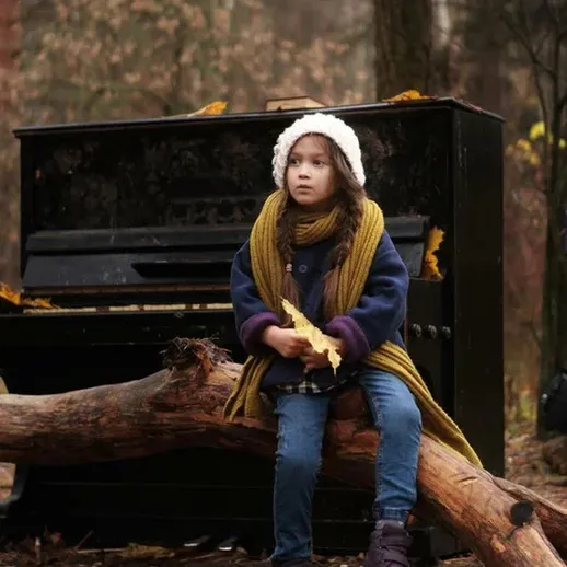 Однажды осенью девочка сидит на бревне возле ржавого пианино в лесу, окруженная листьями и тишиной природы