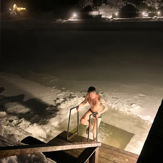 Ночной заплыв в ледяной воде: человек выходит из проруби на зимнем озере