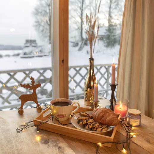 Зимний уют за окном: горячий шоколад с печеньем и ароматная свеча на деревянном столе