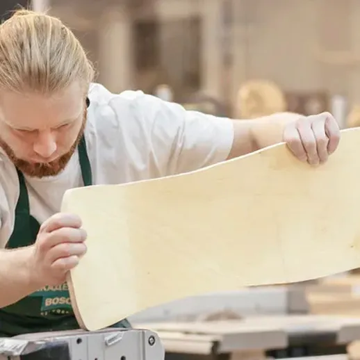 Мастер деревянной работы в мастерской шлифует заготовку для скейтборда в уютной обстановке во время рабочего дня