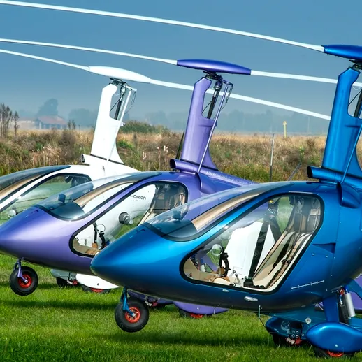 Три различных вертолета на травяном поле, подготовленные к полету в ясный день