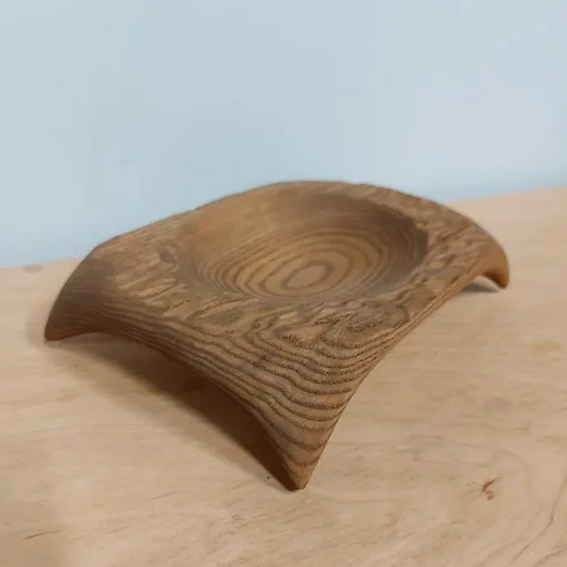 Деревянная подставка необычной формы на деревянном столе в интерьере