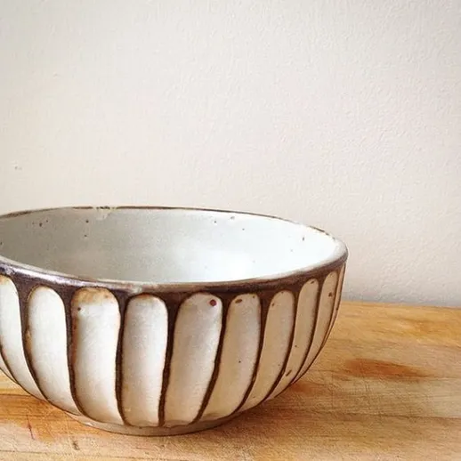 Керамическая чаша с простым узором на деревянной поверхности в домашней обстановке