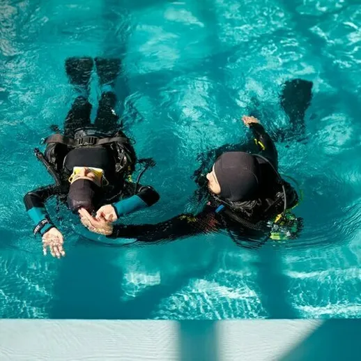 Подводное обучение дайвингу в учебном бассейне, друзья тренируются в воде в яркий солнечный день