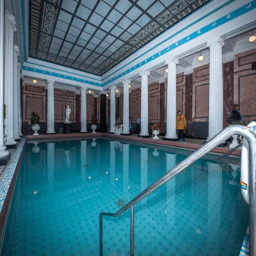 Современный бассейн с колоннами в историческом здании, вечерняя атмосфера с посетителями