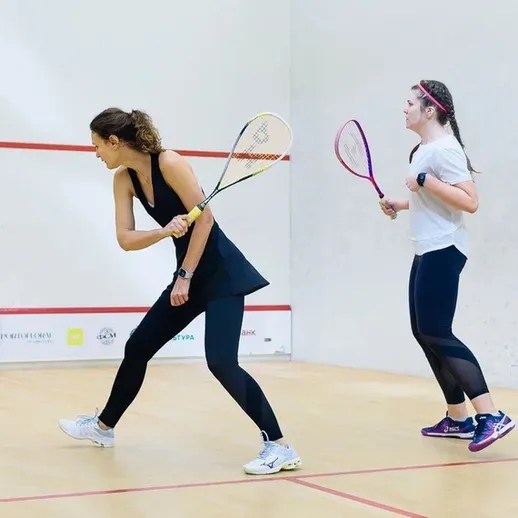 Время игры в сквош: две женщины в спортивной форме на турнире в зале, сосредоточенные на процессе