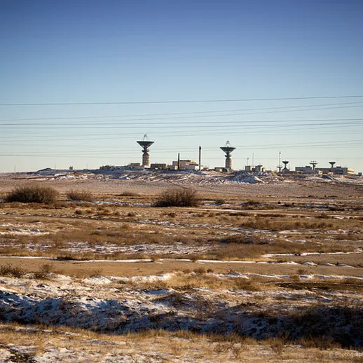 Пейзаж заброшенной промышленной зоны с антеннами на фоне ясного зимнего неба и заснеженной земли