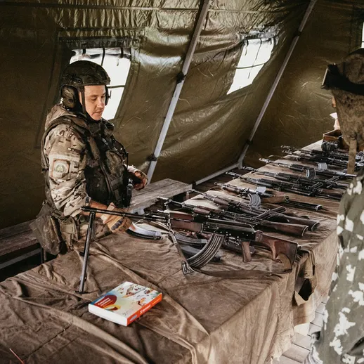 Военные на выставке оружия в полевой палатке в зимних условиях, обсуждающие образцы вооружения