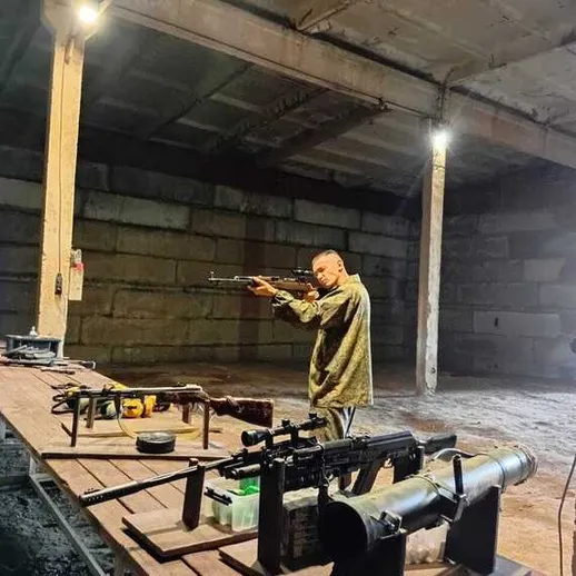 Человек стреляет из ружья на стрельбище в подземном помещении