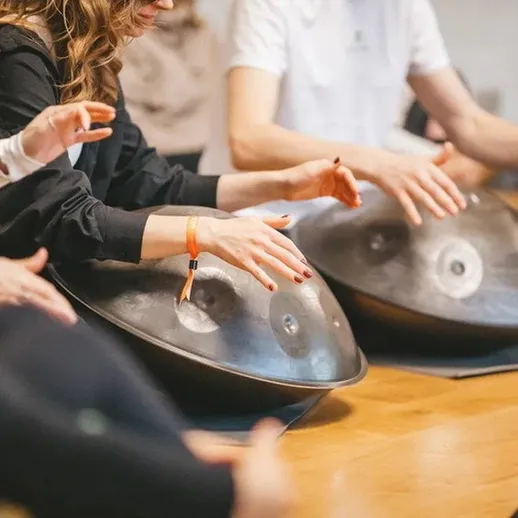 Урок игры на ханге в музыкальной студии с группой людей в уютной атмосфере, вечернее время