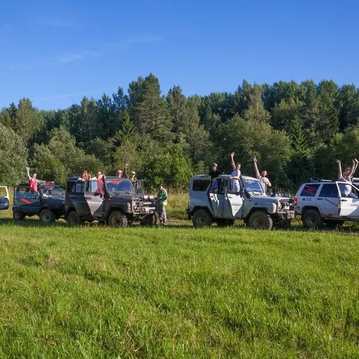 Драйвовые внедорожники на зеленом поле во время экспедиции по пересеченной местности в солнечный день