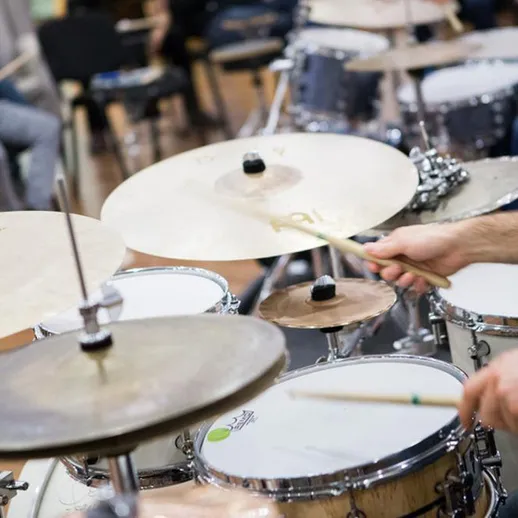 Репетиция на барабанах в музыкальной школе во время вечернего занятия с учениками и преподавателем