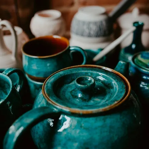 Красивая коллекция глиняной посуды яркого цвета на деревянном столе в уютном кафе