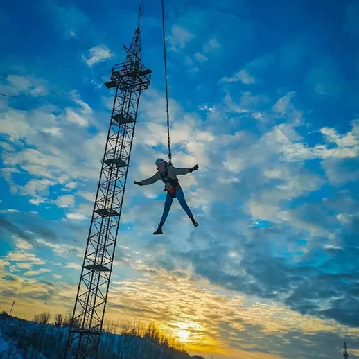 Экстремальный прыжок с вышки на фоне заката в зимнем пейзаже
