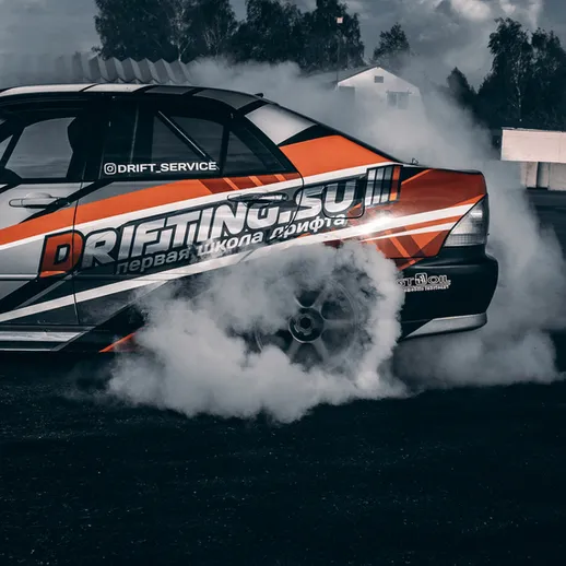 Дрифтовая школа проводит обучение на треке в солнечную погоду, демонстрируя мастерство водителей