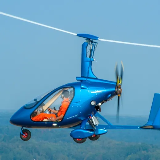 Небо над городом: малый вертолет в полете на фоне голубого неба и зеленых холмов