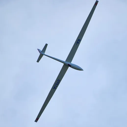 Большой план планера в небе над живописными облаками в ясный день