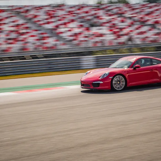 Красный спортивный автомобиль на гоночной трассе во время соревнований в солнечный день