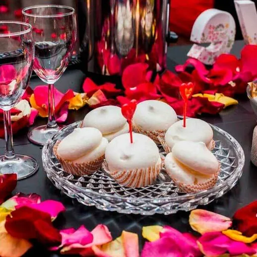 Праздничный стол с капкейками и цветочными лепестками для романтического вечера