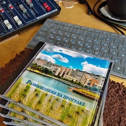 Альбом с фотографиями о путешествии по набережной города, размещённый на столе рядом с оборудованием для записи звука