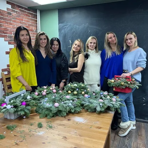 Женщины создают рождественские венки на мастер-классе в уютной студии