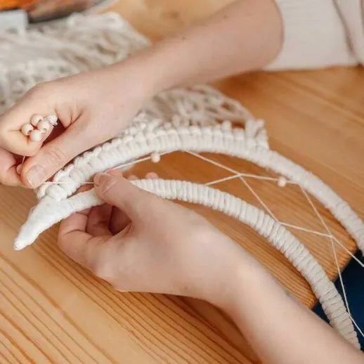 Создание текстильного искусства: руки художника работают над оригинальным браслетом из веревки и бусин