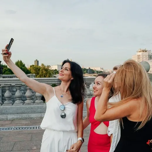 Группа женщин делает селфи на мосту в Москве в летний вечер