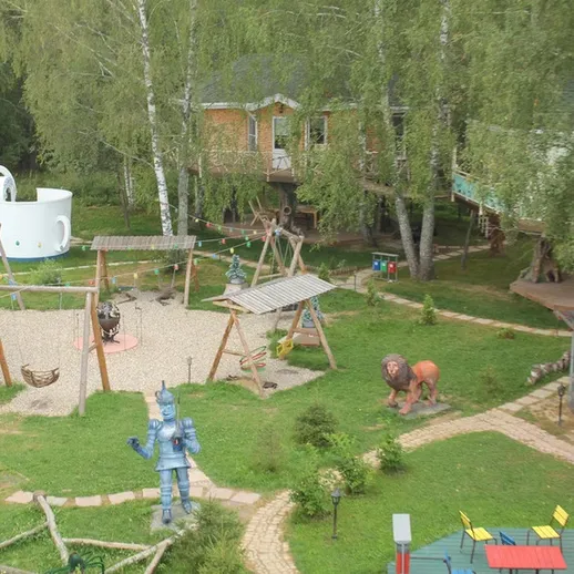 Уютный детский игровой парк с аттракционами и зелеными деревьями в ясный день