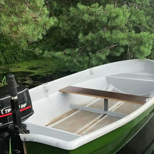 Лодка на спокойной воде среди зеленых деревьев в летний день