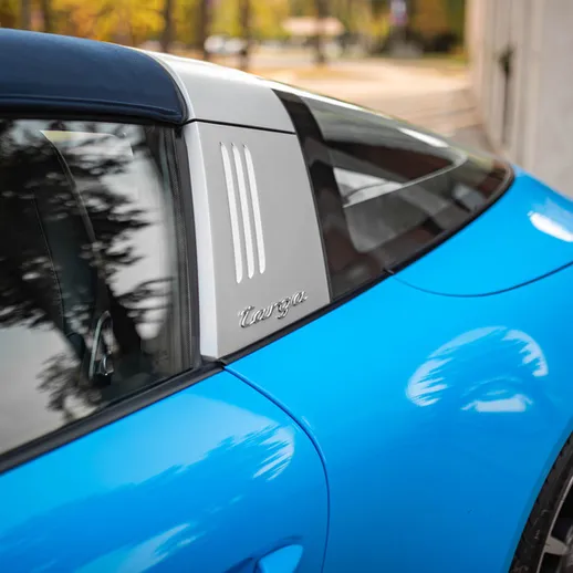 Синий спортивный автомобиль стоит на улице среди деревьев и зданий