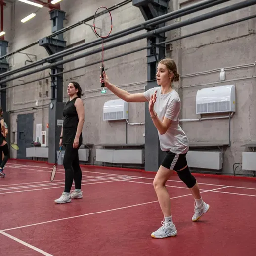 Девушки играют в бадминтон в спортзале на турнире, проводимом в октябре, с весёлой атмосферой и тренировками