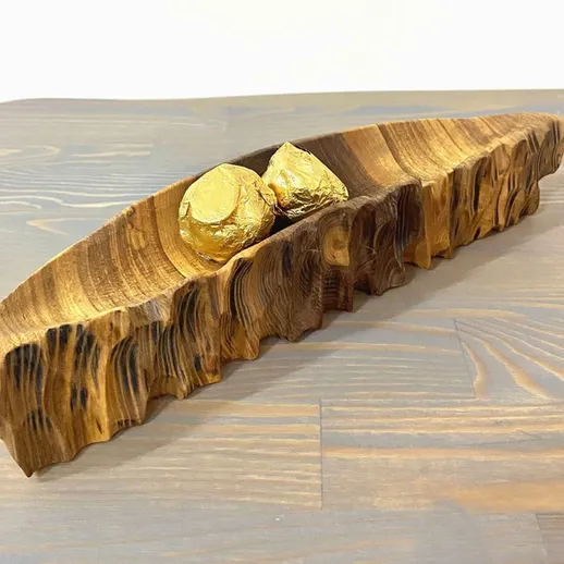 Деревянное блюдо с закругленными краями и украшением из камней на деревянной поверхности