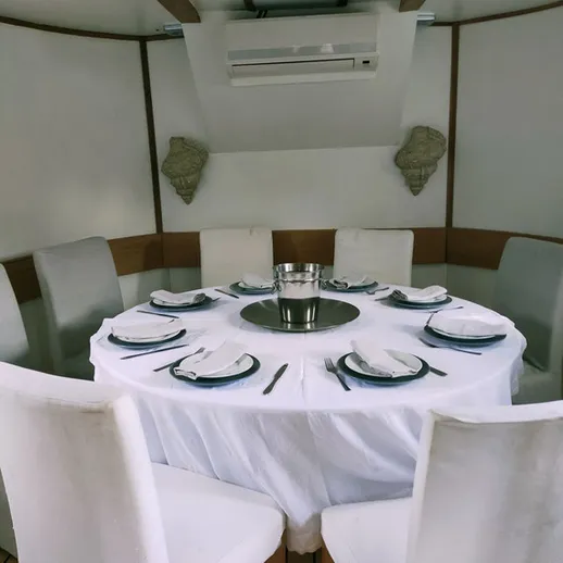 Элегантный стол для обеда в уютной комнате на яхте, окруженной стильными стульями и с серебряными приборами