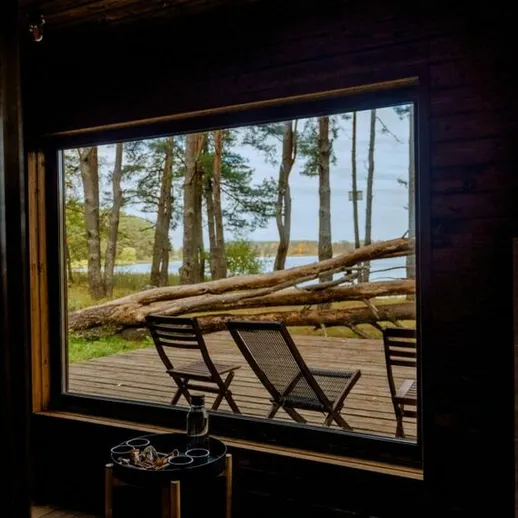 Уютный интерьер с окнами на лес и водоем в тишине загородного дома в летний день