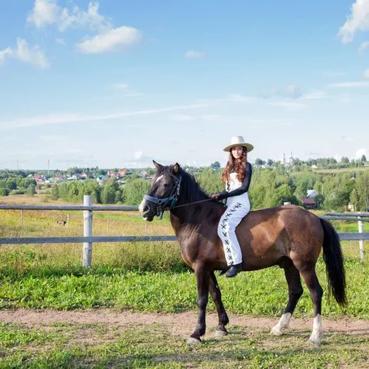 Женщина верхом на лошади в живописном сельском ландшафте под ясным небом