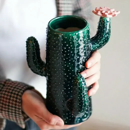 Оригинальная кружка в форме кактуса, которую держит человек с любовью к необычной посуде, в уютной обстановке дома