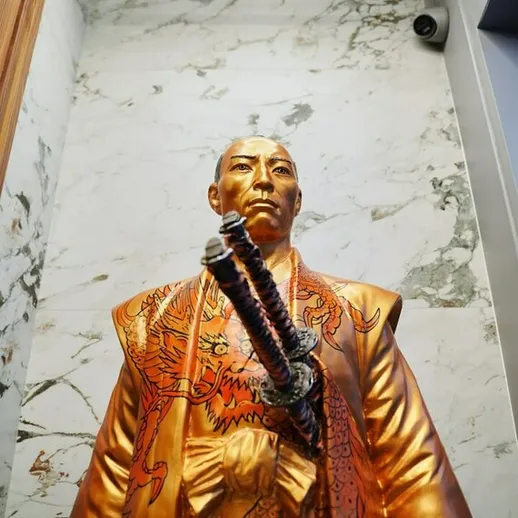 Золотая статуя самурая с мечом в мармуровом интерьере, выполненная в стиле японской традиции