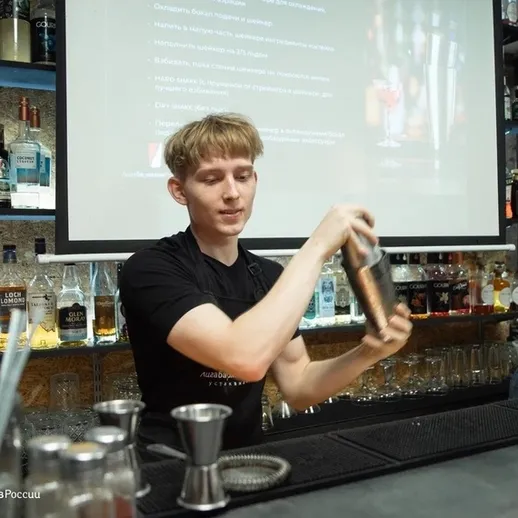 Бармен энергично смешивает коктейль в современном баре во время вечернего мероприятия