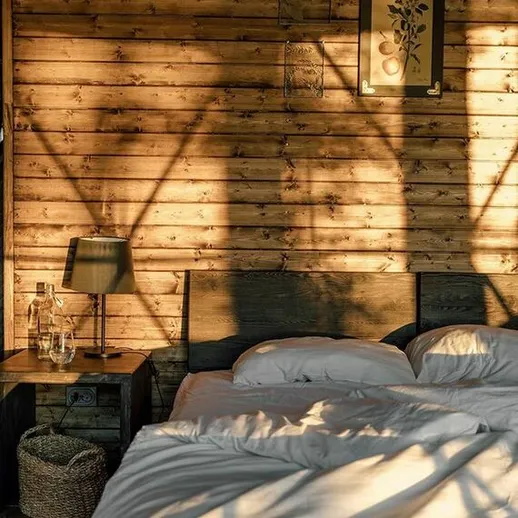 Уютная спальня с деревянными стенами и солнечными тенями, созданными вечером