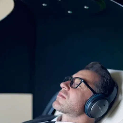 Мужчина в деловом костюме использует оборудование для расслабления и улучшения концентрации в современном кабинете