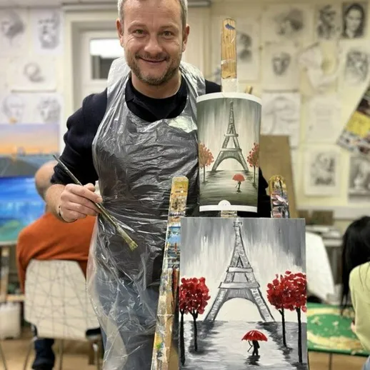Художник создает картину с Эйфелевой башней в студии живописи, среди участников занятия