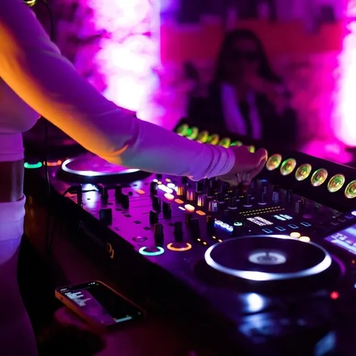 Диджей за пультом создает атмосферу вечеринки в клубе с яркими огнями