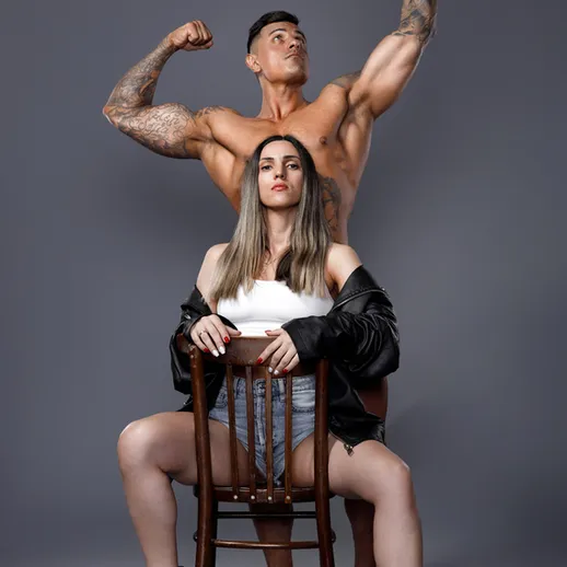 Фитнес-пара демонстрирует силовые позы на фоне нейтральной стены в студии